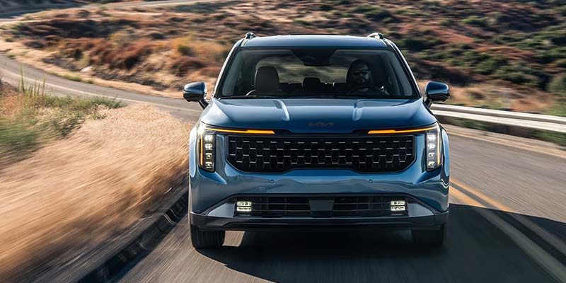 Blue Kia SUV driving on road
